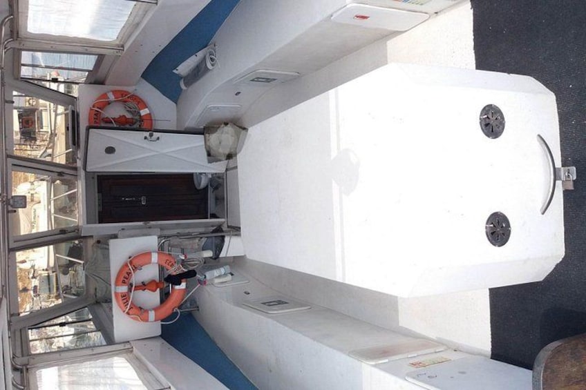A boat's interior with a steering wheel, life rings, and a control panel. 5
