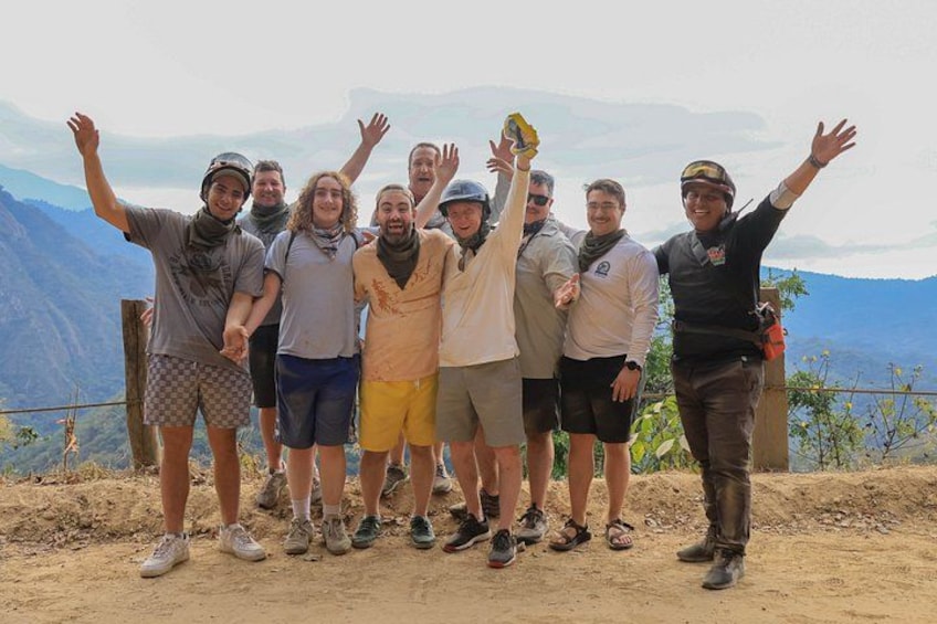 A group of people standing on a dirt path with mountains in the background. 1