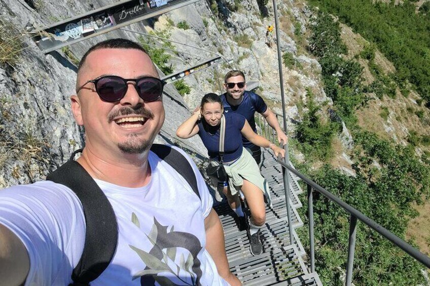 A person taking a selfie on a metal staircase with a rocky landscape in the background. 5