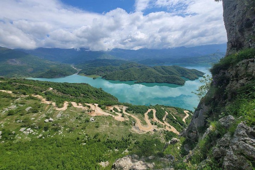 A mountainous landscape with a turquoise lake surrounded by greenery and a clear sky. 2