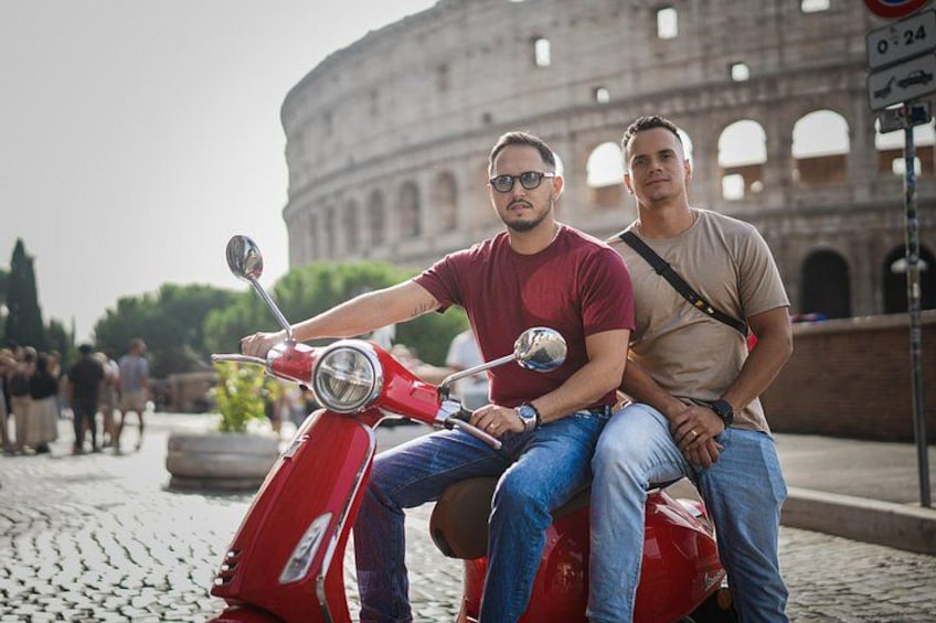 Two people on a red scooter with the Colosseum in the background. 3