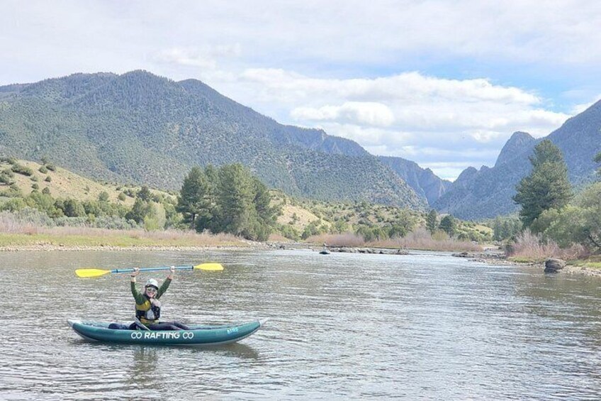 A person kayaking on a river with mountains in the background. 5