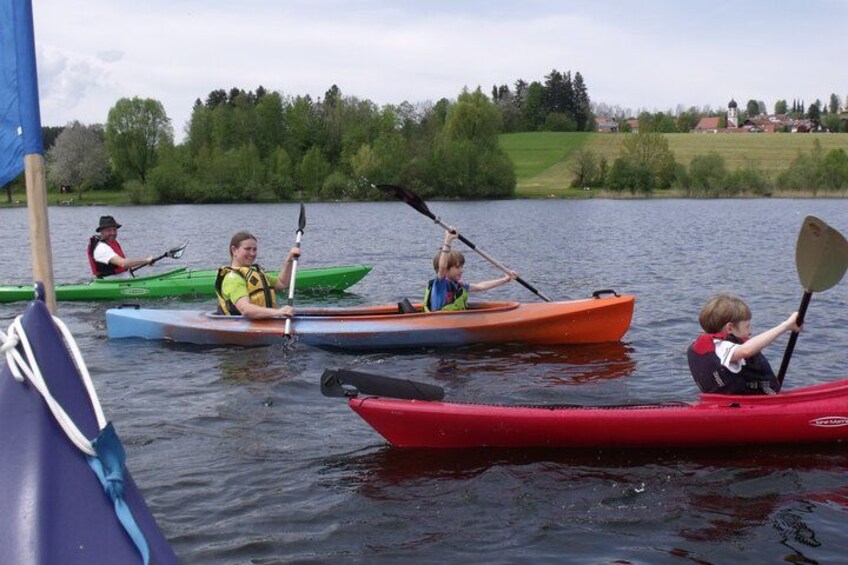 Personas haciendo kayak en un lago tranquilo rodeado de vegetación. 1