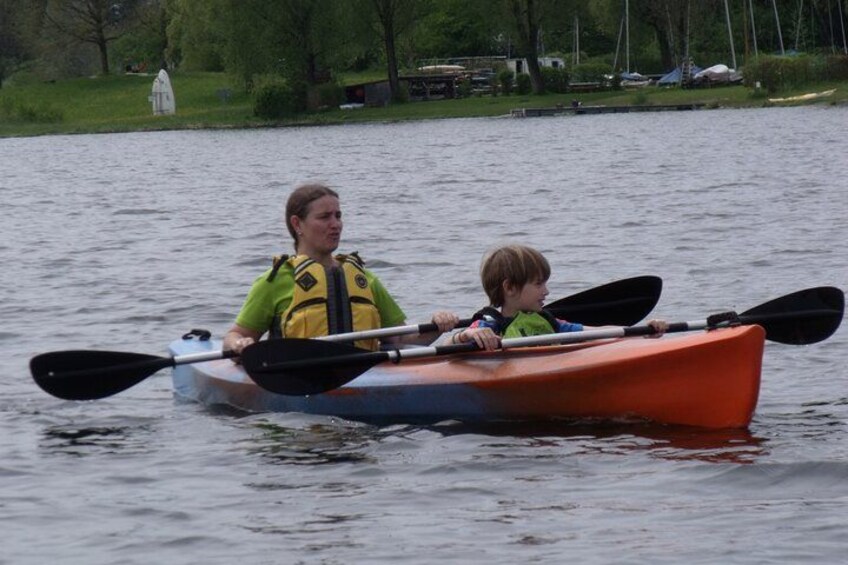 Dos personas kayakando en un lago tranquilo rodeado de vegetación. 3