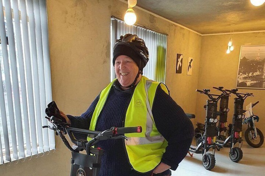 Une personne se tient à l’intérieur, près d’un vélo, et porte un gilet de sécurité et un casque. 2