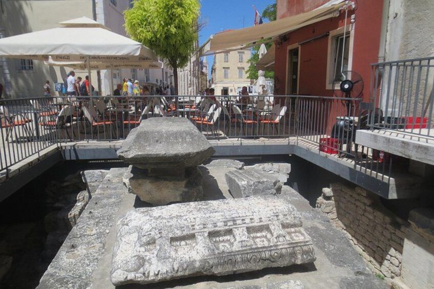 A stone monument in an outdoor café area with tables and chairs. 4