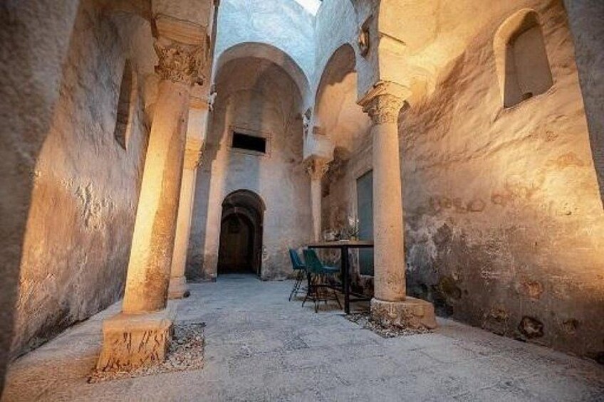 Un ancien couloir en pierre, orné de colonnes, avec une table et des chaises. 1