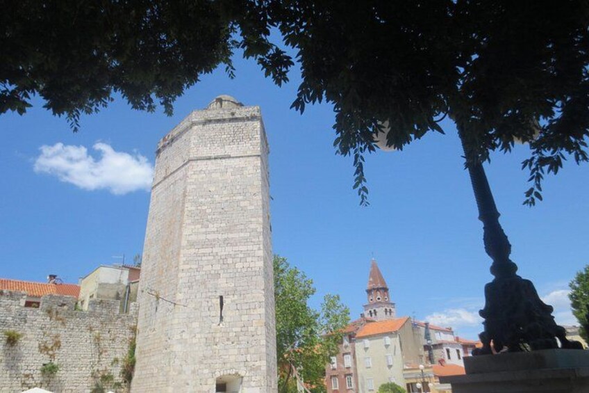 A stone tower, a church with a red roof, and a tree. 5