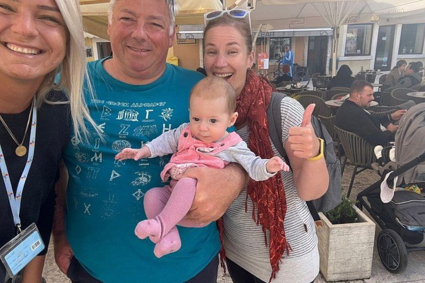 A person holding a baby, a man in a teal shirt, and a woman with a red scarf. 2
