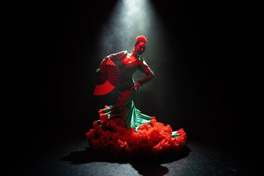 A person in a red and green outfit with a fan, standing on a red base. 2