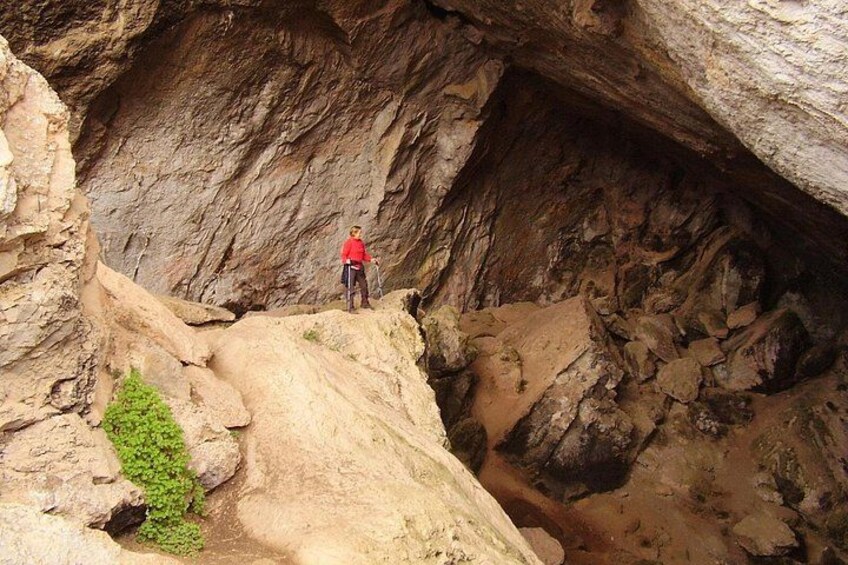 A person standing on a rock ledge in a rocky canyon with a narrow passageway. 5