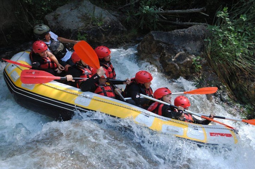 A group of people in a yellow inflatable raft navigating a river with rapids. 4