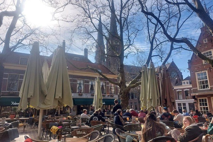 Outdoor seating with umbrellas, a café, and buildings in the background. 1