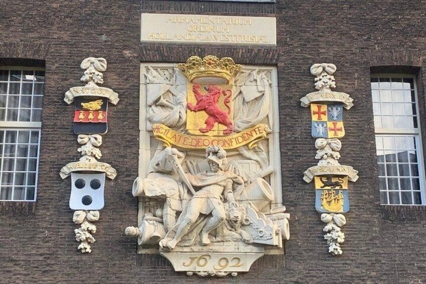 Eine Gebäudefassade mit Wappen, heraldischen Schildern und dem Jahr 1802 unter dem mittleren Schild. 3