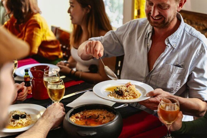 A group of people dining at a table with food and drinks. 1