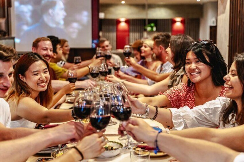 A group of people toasting with wine glasses at a dinner table. 3