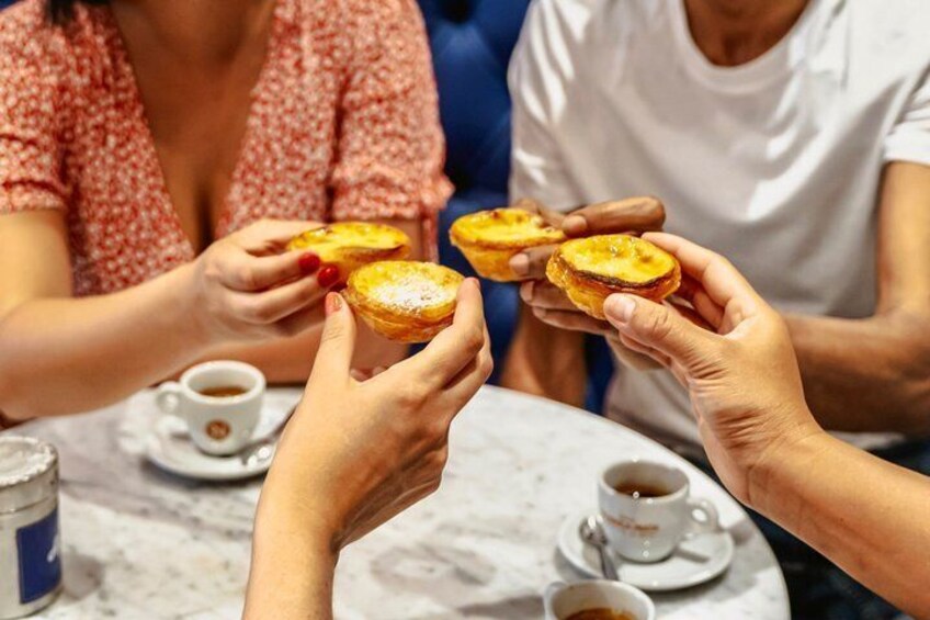 People holding pastries at a table with coffee cups. 4