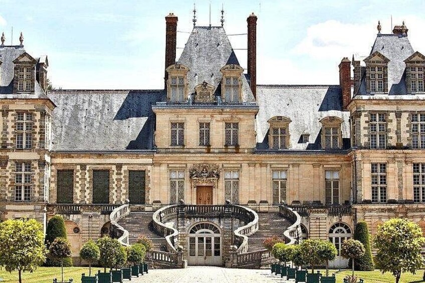 A historic building with a central staircase, multiple chimneys, and a symmetrical facade. 3