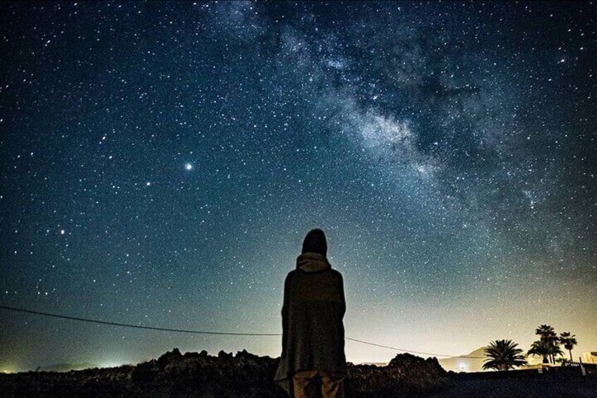 A person standing under a starry night sky with a visible Milky Way. 2