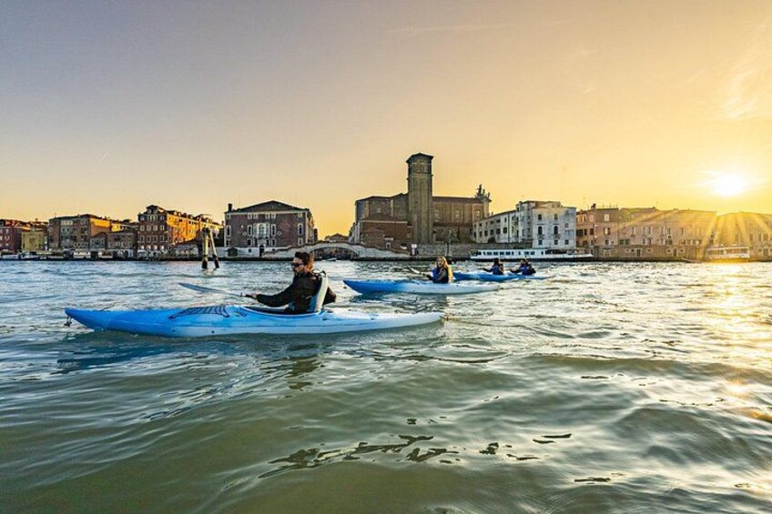 Kayakers on a river with a cityscape in the background. 1