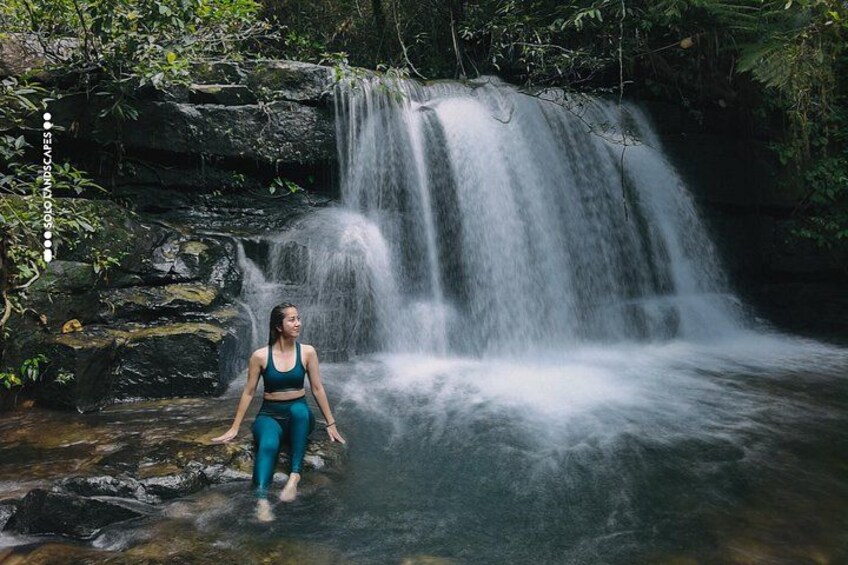 A waterfall with a person standing in the water. 2