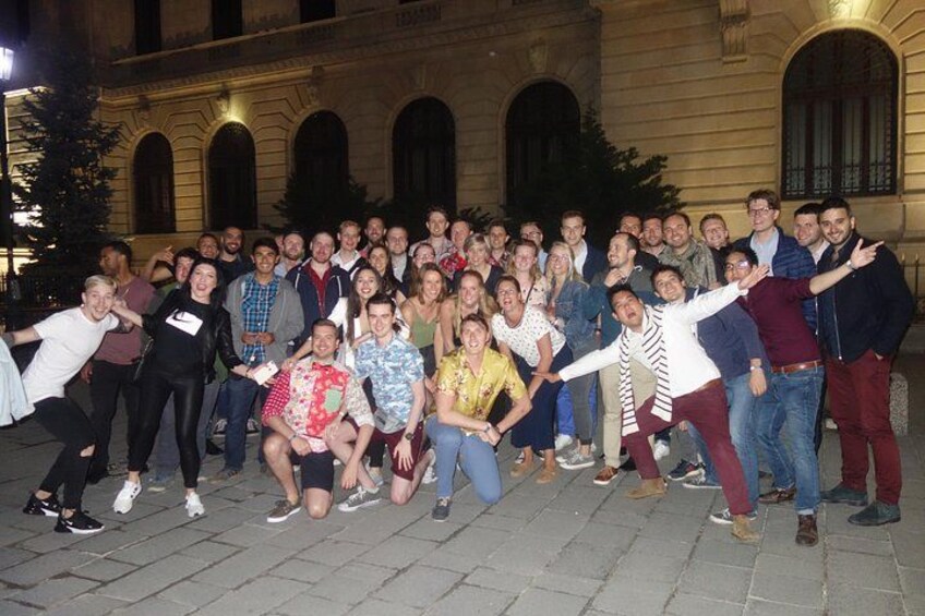 A group of people posing for a photo in front of a building with arched windows. 1