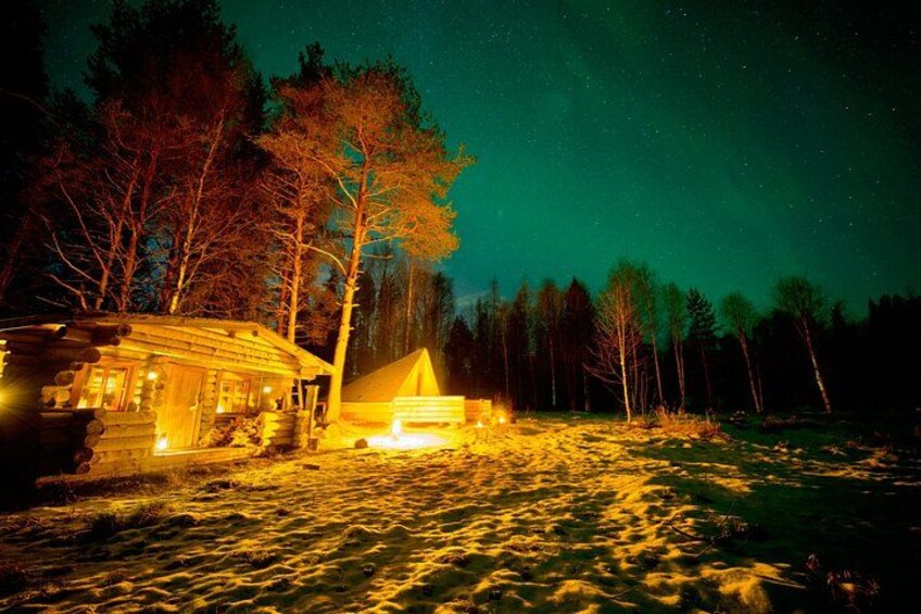 A cabin with a lit interior, surrounded by a snowy landscape and a forest at night. 4