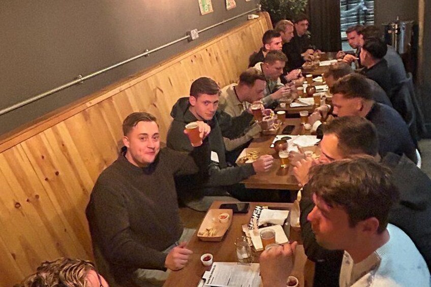 A group of people dining at a restaurant with wooden booths and tables. 3