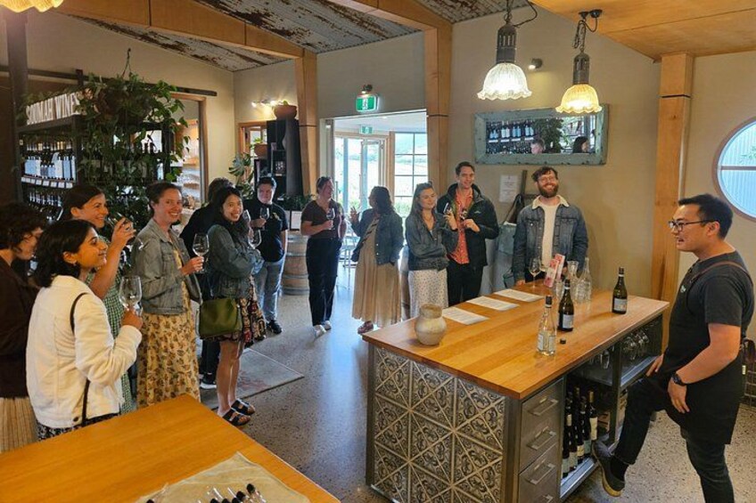 A group of people standing around a bar area with bottles and glasses. 2