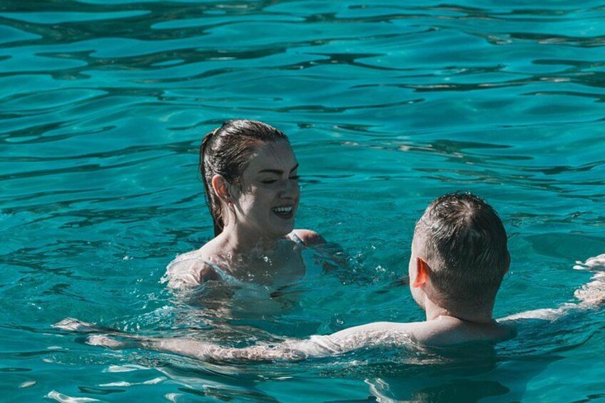 Two people swimming in clear blue water. 4