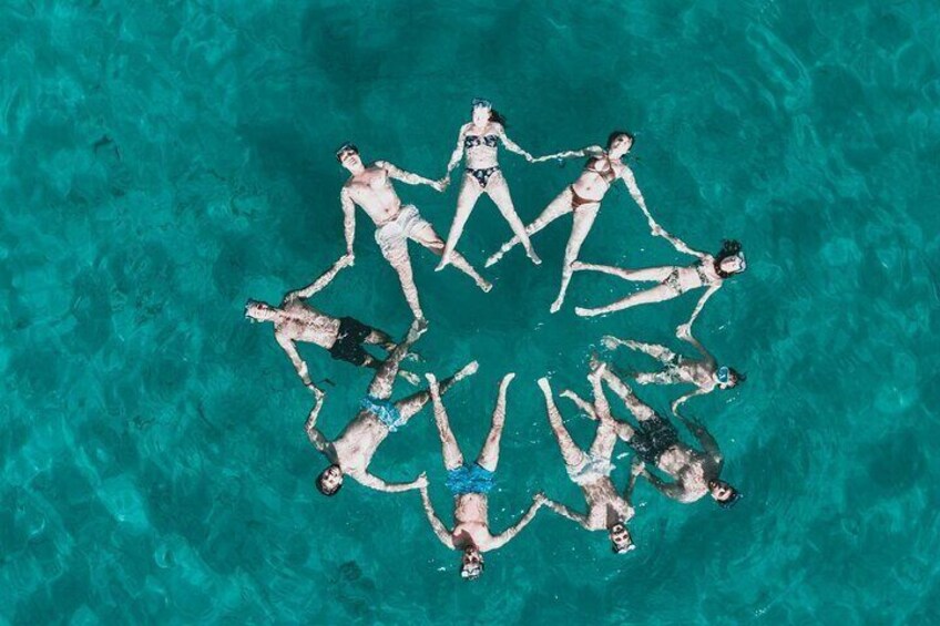 Vista aérea de personas flotando en círculo en una piscina turquesa. 3