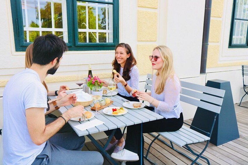 Three people dining at an outdoor table with food and drinks. 3