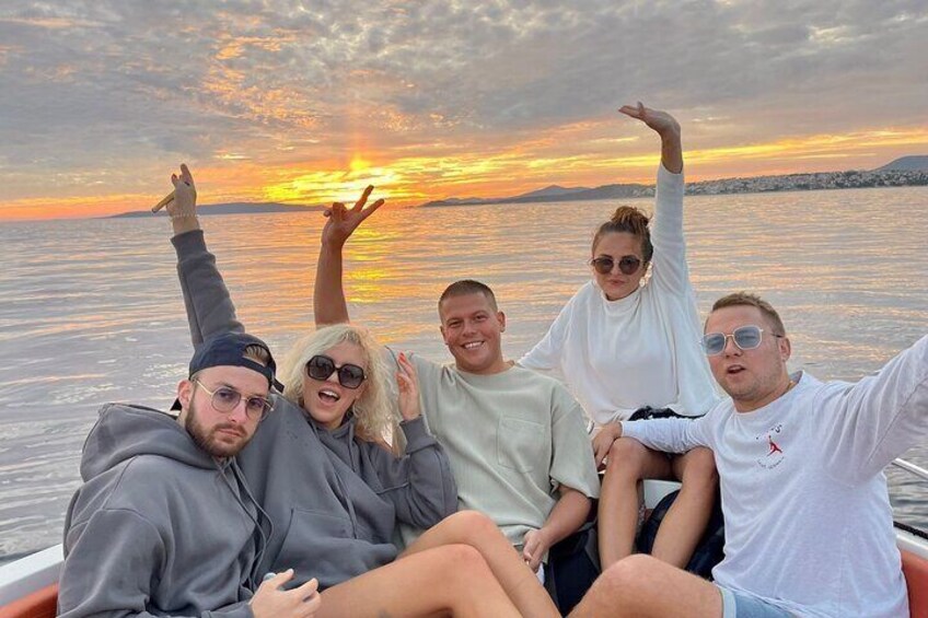 A group of people on a boat during sunset with a calm sea and distant shoreline. 5