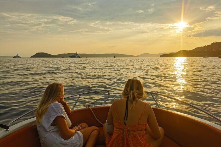 Two people in a boat on a body of water with a sunset in the background. 4