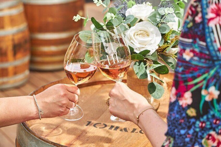Two people toasting with wine glasses, a wooden barrel, and a floral arrangement. 2