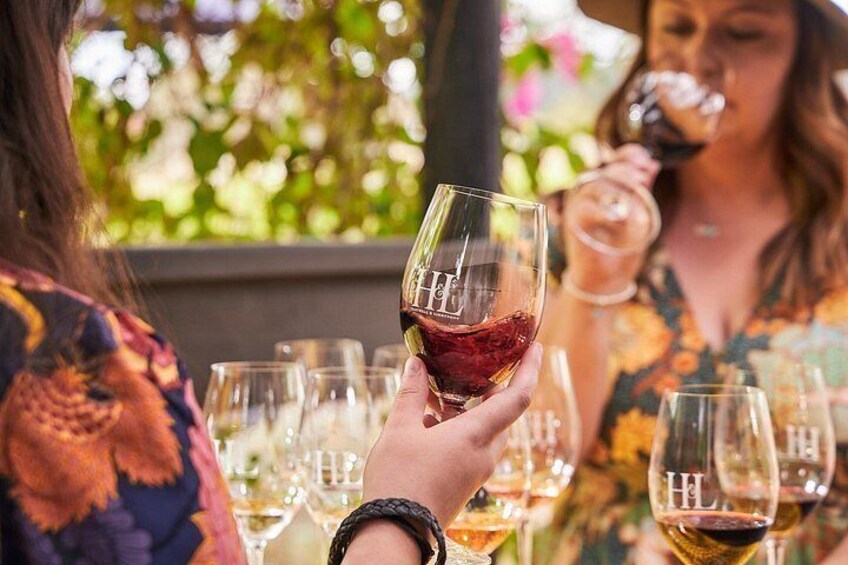 A person holding a wine glass with a red liquid, surrounded by other wine glasses. 3