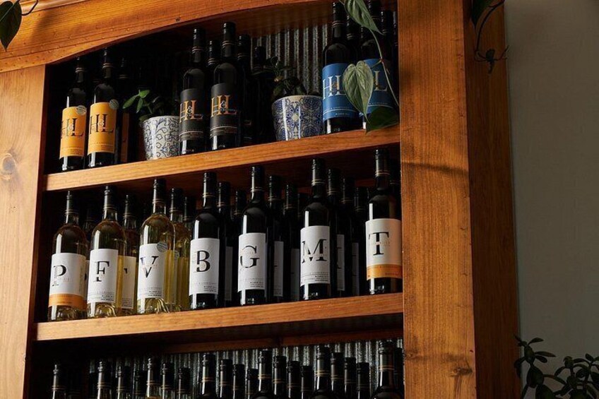 A wooden wine rack with bottles labeled with letters. 5