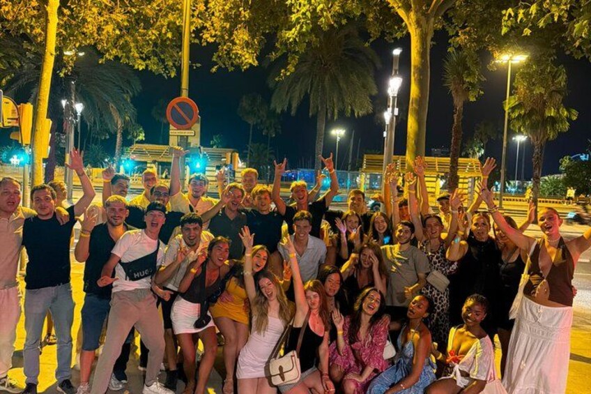 A group of people posing for a photo in an outdoor setting with trees and street lamps. 1