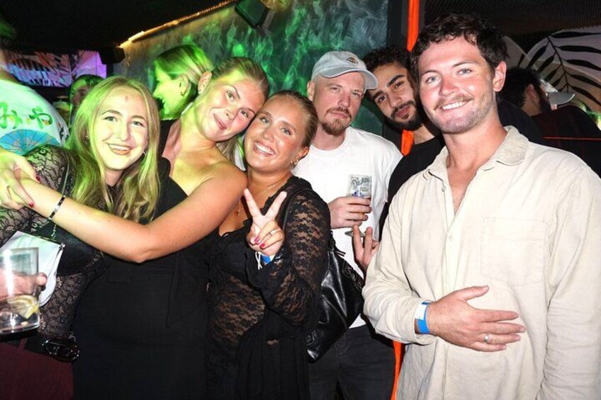 A group of people at a social event with a green-lit background. 2
