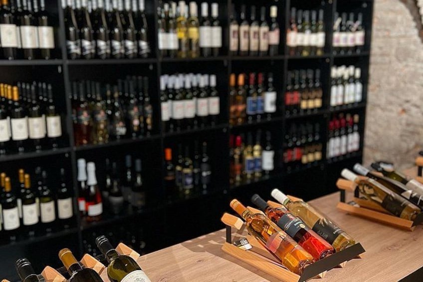 Une cave à vin avec des étagères remplies de bouteilles et une sélection de bouteilles disposées sur une table en bois. 1