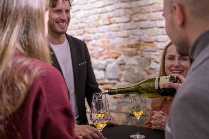 Un groupe de personnes est assis autour d’une table, et du vin est versé dans des verres. 2