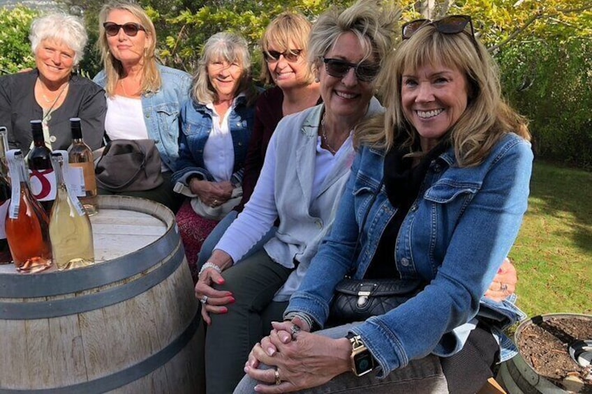 Un grupo de personas sentadas alrededor de un barril de madera con botellas. 2