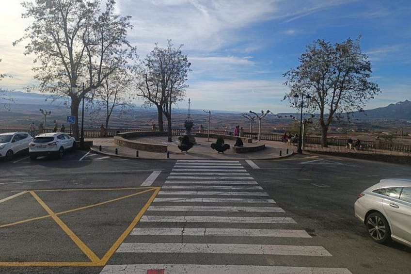 A parking lot with cars, a pedestrian crossing, and trees. 5