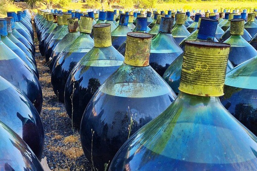 Rows of large, dark-colored glass bottles with metal caps, likely for storage or transport. 5