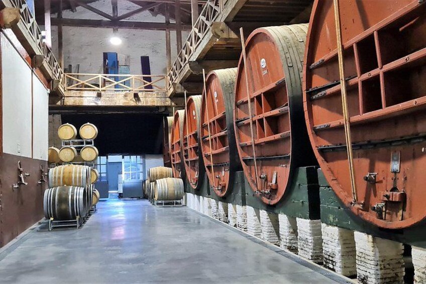A warehouse with large wooden barrels lined up against the walls. 3