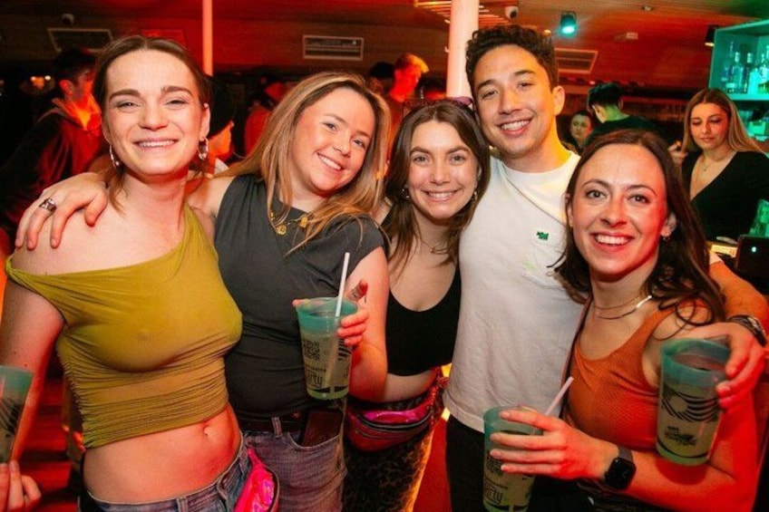 Un grupo de personas en un encuentro social, sosteniendo bebidas y posando para una foto. 4