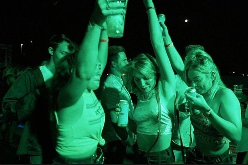 Een groep mensen bij een evenement buiten, sommigen met drankjes. 1