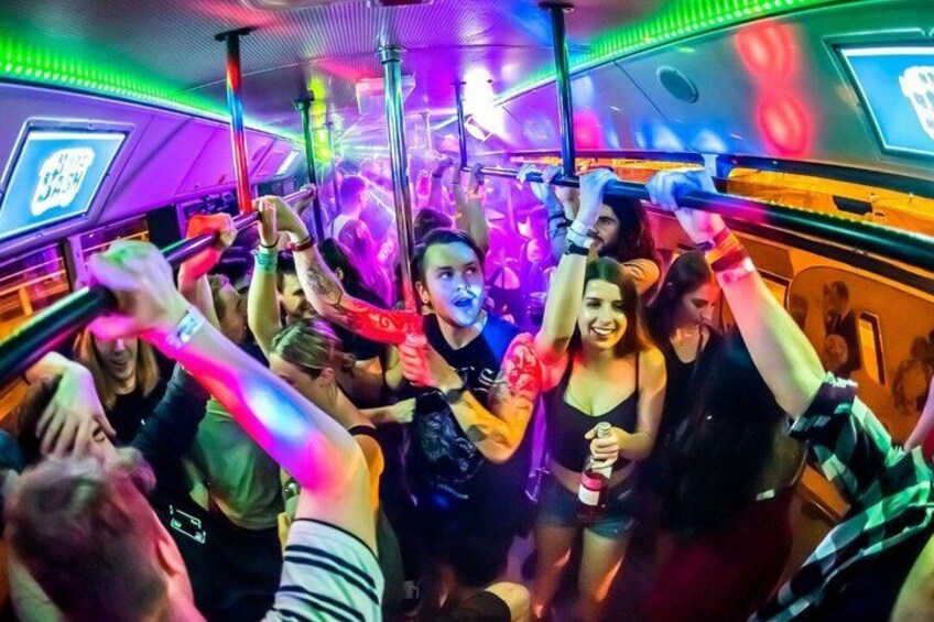 Un vagón de metro abarrotado, con pasajeros agarrados a las barras, iluminado por luces de colores. 3