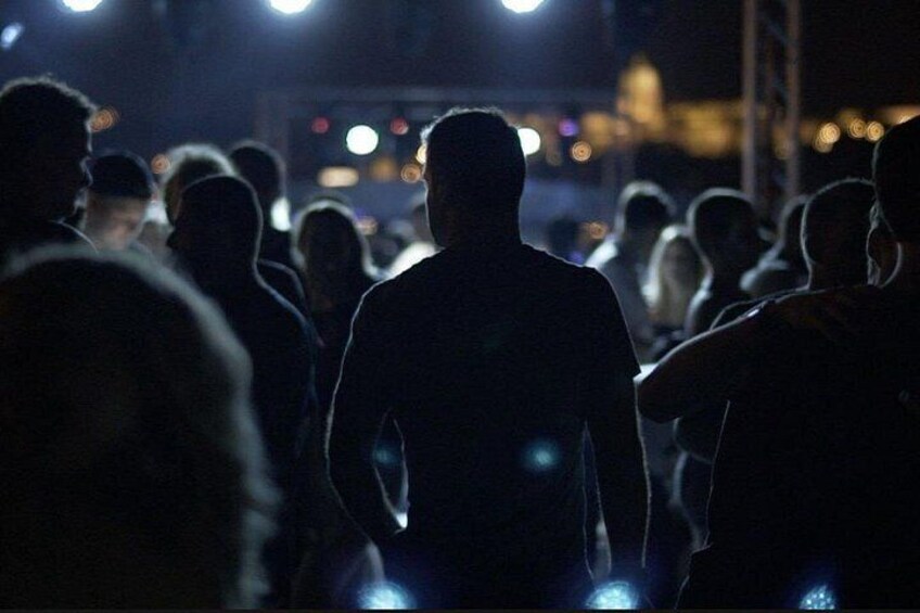 A crowd of people walking at night with artificial lighting. 4