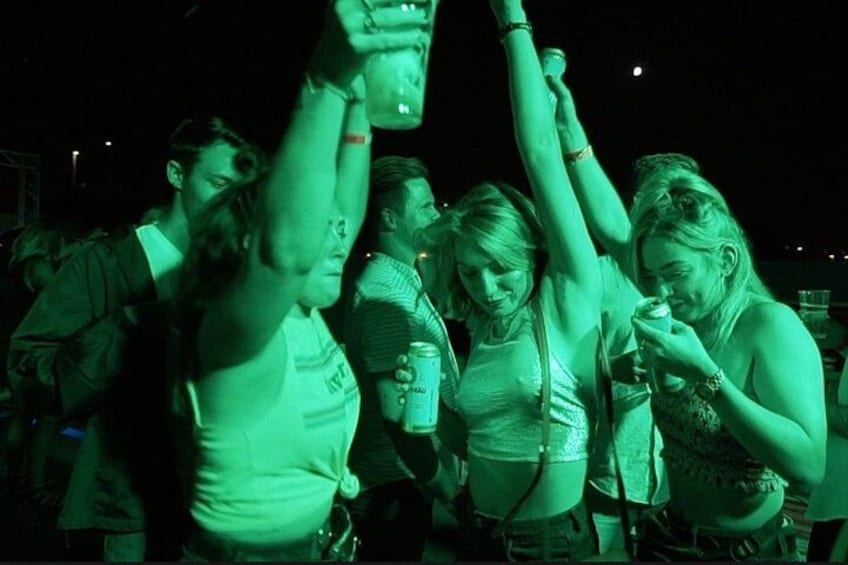 Un grupo de personas en un evento al aire libre, algunas sosteniendo bebidas. 1